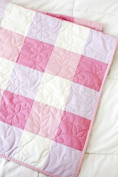 a pink and white quilt on a bed