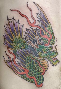 a colorful dragon tattoo on the back of a man's stomach, with red and green flames coming out of it