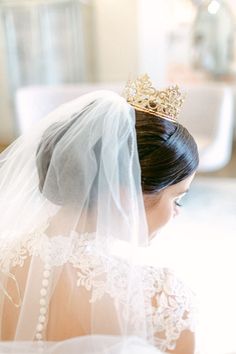 a woman wearing a veil with a tiara on her head and looking down at the ground