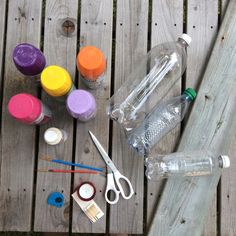 the supplies needed to make an art project are laid out on a wooden deck, including water bottles and scissors