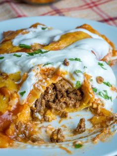 a close up of a plate of food with meat and cheese on top, covered in sour cream