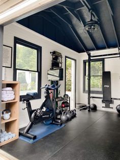 a home gym with exercise equipment in the middle and windows to the side, along with other items