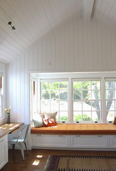 a window seat in the corner of a room with white walls and wood flooring