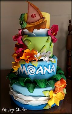 a multi layer cake decorated with flowers and a sailboat on top that says moan