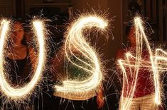 two people holding sparklers in their hands with the word us spelled out by them