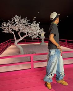 a young boy standing in front of a bonsai tree