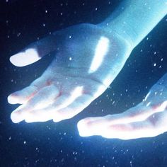 two hands reaching out to touch each other in the dark, with snow flakes all around them