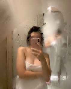 a woman in a white dress taking a selfie with her cell phone while standing in front of a mirror