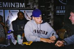 a young man sitting at a table signing autographs