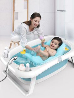 a woman is playing with her baby in the bathtub