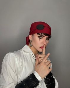 a woman in white shirt and red bandana holding her finger up to her mouth