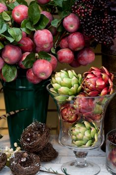 an arrangement of flowers and fruit in glass vases