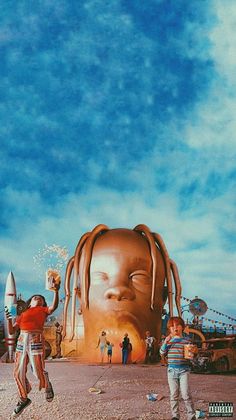 two young boys standing in front of a giant head with long dreadlocks on it