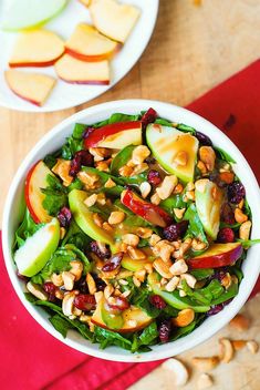 two bowls filled with fruit and nuts on top of a wooden table next to a red napkin