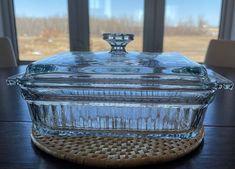 a glass casserole sitting on top of a wooden table next to a window