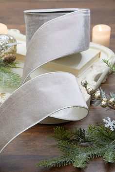 two rolls of silver satin ribbon sitting on top of a table next to christmas decorations