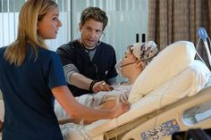 a man in a hospital bed being tended to by two women