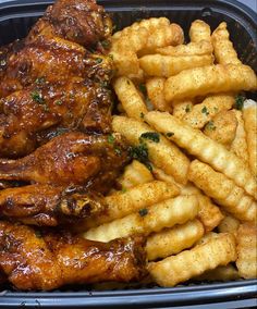 a plastic container filled with chicken wings and fries