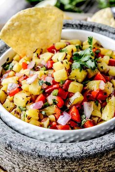 a white bowl filled with pineapple salsa and a tortilla chip