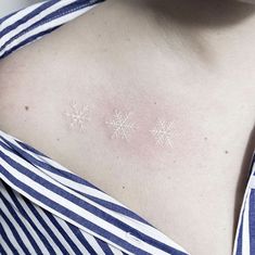 a woman's chest with three snowflakes on the back of her shoulder