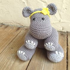 a crocheted hippo sitting on top of a wooden floor next to a wall