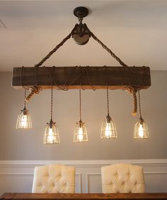 a light fixture hanging from the ceiling over a dining room table with four white chairs