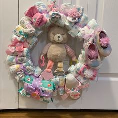 a teddy bear sitting in the middle of a wreath made out of diapers and other items