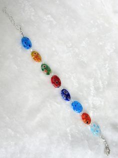 This multi-colored adjustable millefiori bracelet set is made with 14mm flat ovals and includes blue, red, orange, and green multi-colored beads. The bracelet adjusts from 7 inches to 8 inches. The earrings dangle 1 inch from the loops of the silver plated ear wires. This set will be slipped into an organza bag and shipped in a bubble mailer. Millefiori Bracelet, Oval Earrings, Oval Earring, Orange And Green, Bubble Mailer, Earrings Dangle, Organza Bags, Ear Wires, Bracelet Set