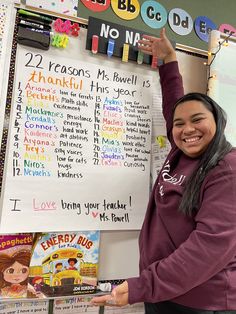 a woman is standing in front of a bulletin board