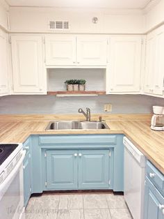 an empty kitchen with blue cabinets and white appliances, including a dishwasher on the stove