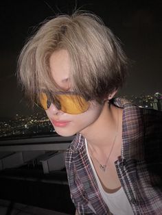 a woman with blonde hair and sunglasses on top of a building at night, looking off into the distance