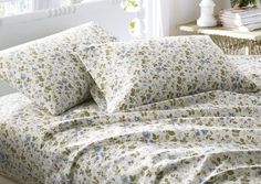 a bed with floral sheets and pillows on it