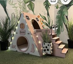 there is a cat house made out of cardboard with lights on the roof and stairs