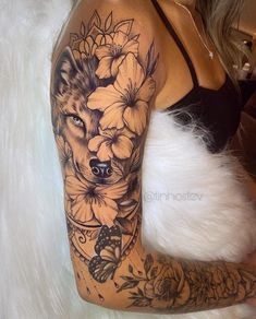 a woman's arm with flowers and a wolf tattoo on the left side of her body