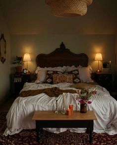 a bed with pillows and blankets on top of it next to two lamps in a room