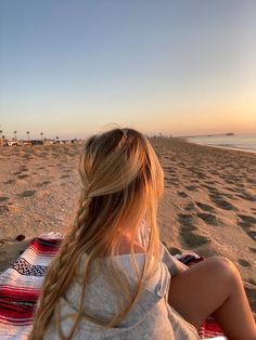 a woman sitting on top of a beach next to the ocean