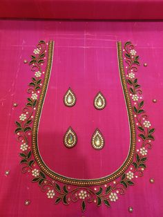 an embroidered pink cloth with gold and green beads on the neck, along with two matching necklaces