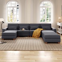 a living room with large windows and a sectional couch in the middle of the room