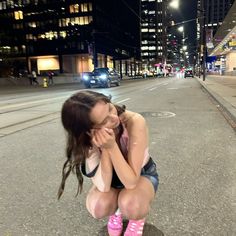 a woman kneeling down on the side of a road