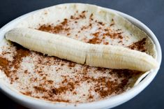 a banana sitting on top of a white bowl filled with cinnamon and powdered sugar