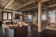 a living room filled with lots of furniture and wooden beams on the ceiling next to windows