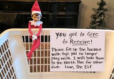 an elf is sitting in a basket next to a sign that says you got to give to receive