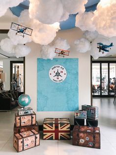 several suitcases are stacked up in front of a blue wall with clouds hanging from it