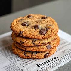 a stack of chocolate chip cookies sitting on top of a newspaper