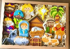 decorated cookies in a box with nativity scene on top and palm trees around it