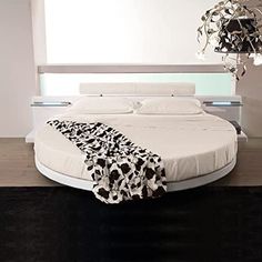 a round bed with a black and white comforter on it's headboard