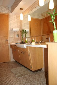 a bathroom with wooden cabinets and tile flooring next to a plant in a vase