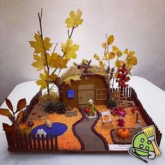 a cake made to look like a house with fall leaves on the roof and yard