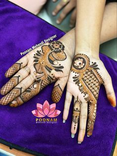 two hands with henna designs on them sitting on a purple mat next to each other