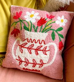 a pink pillow with flowers on it sitting on a chair next to a stuffed animal